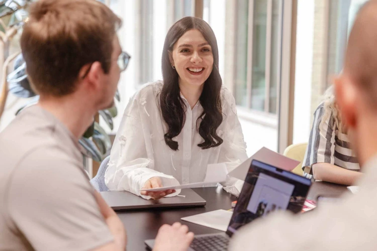 Woman in white top sat smiling.