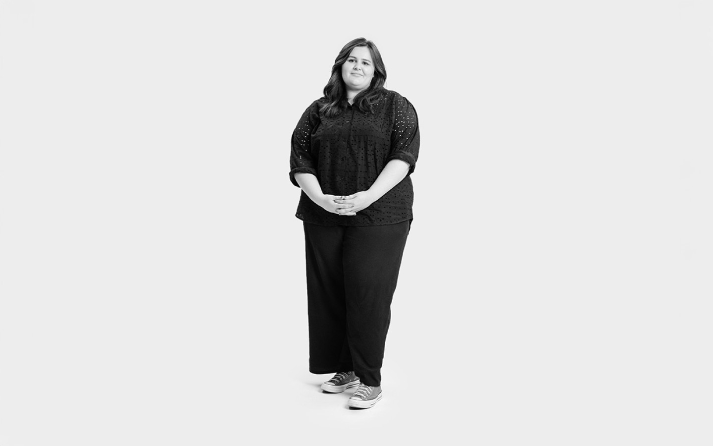 Woman in black top and trousers stood with hands together.